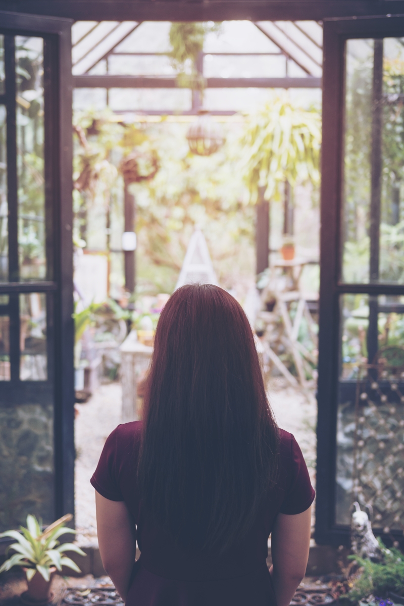 Lonely Woman looking ahead to corridor view of garden