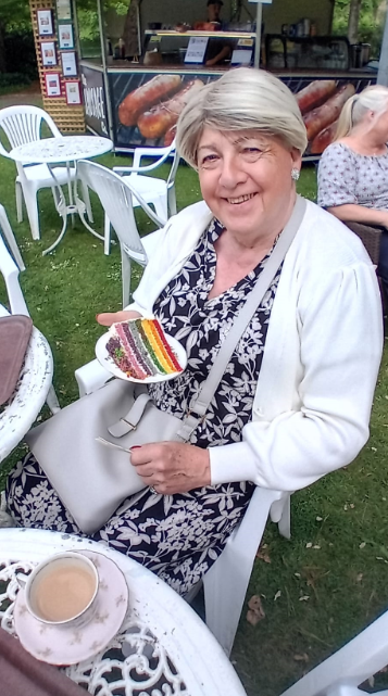 Deborah, a meber having tea with an LGBGTQ flag in sand on a plate